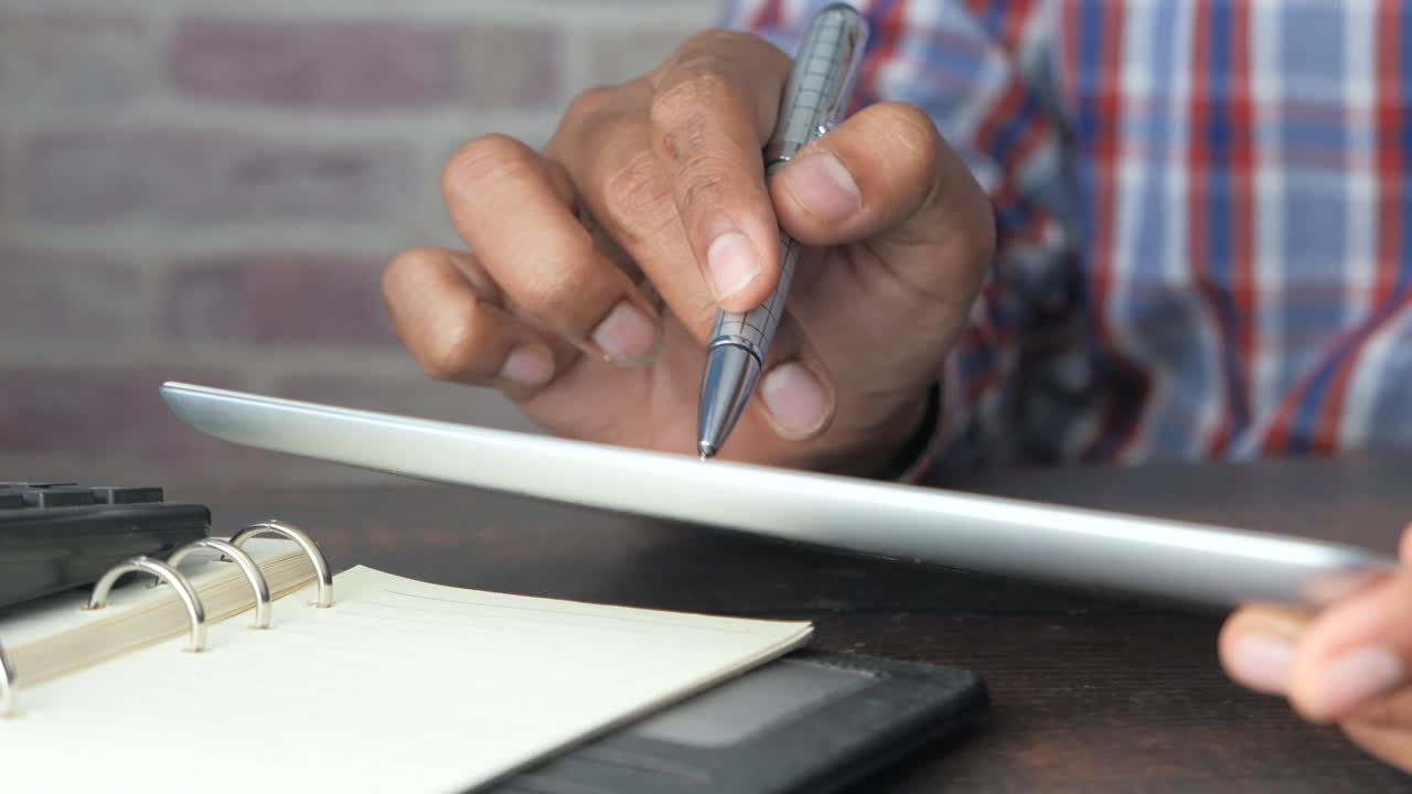 persona que utiliza una tableta, un bolígrafo y un cuaderno