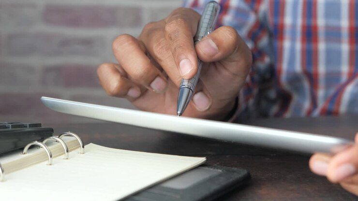Person Using Tablet, Pen, and Notebook
