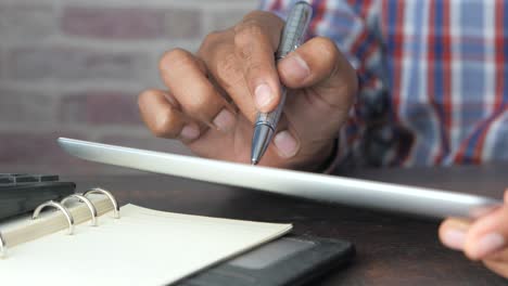 person using tablet, pen, and notebook