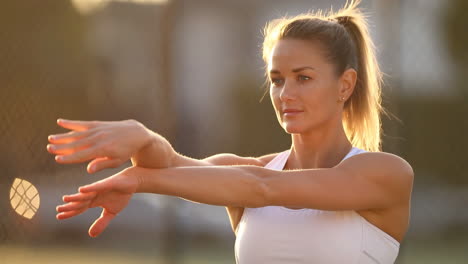 young woman stretching her arms outdoors during golden hour