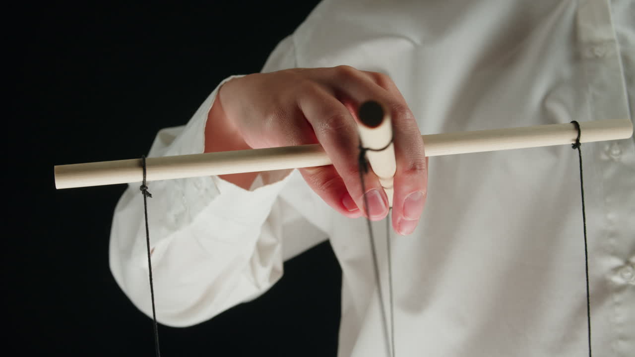 Close-up of Hand Manipulating Puppet Control Bar with Strings