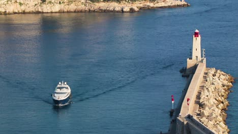 port in nice, southern france, seen from above (bird's eye). boat-yacht passes by lighthouse and comes toward camera,