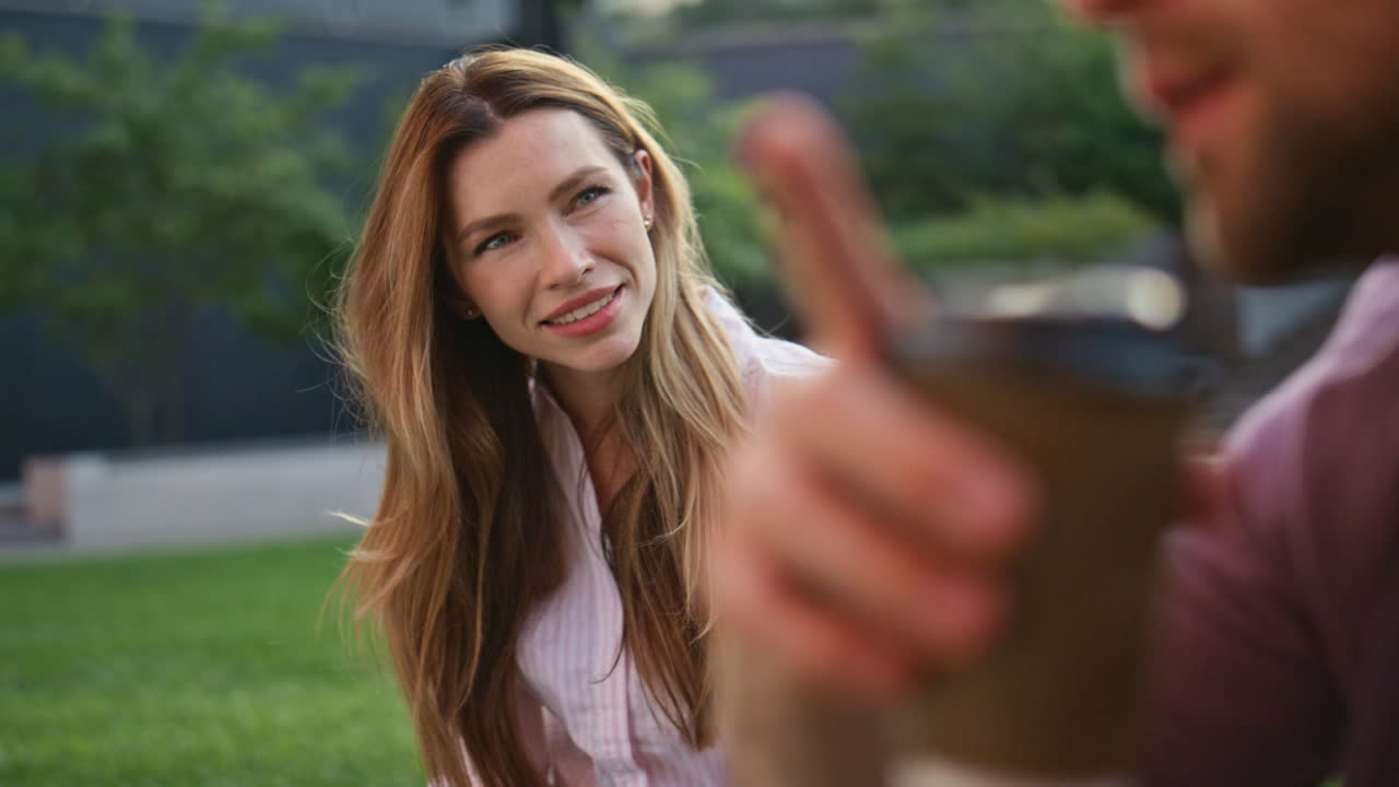 manos sosteniendo una taza de café en el césped verde en primer plano. amigos relajados disfrutando de un picnic