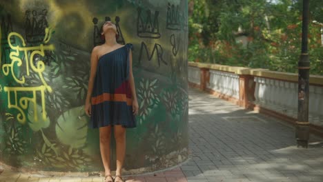 Una-Mujer-India,-Vestida-Con-Un-Vestido-Vibrante,-Mira-A-La-Cámara-Y-Al-Cielo-Expansivo,-Su-Cabello-Adornado-Con-Fotos,-Mostrando-Su-Rica-Herencia-Cultural-Y-Su-Presencia-Cautivadora