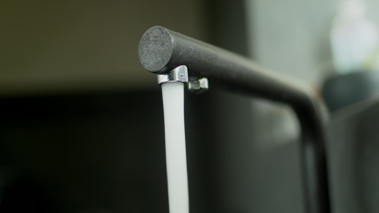 una corriente de agua fluye desde un elegante grifo de cocina de grafito