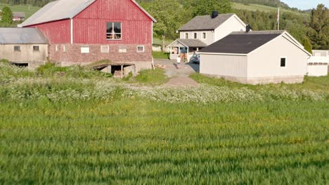 pullback over vintage farmhouses at the rural landscape with mountains and spring field meadows