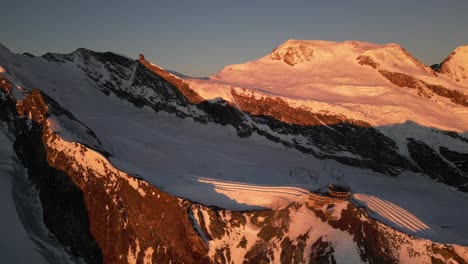 aerial panning shot: mountain ridge with a blue sky in the background, switzerland