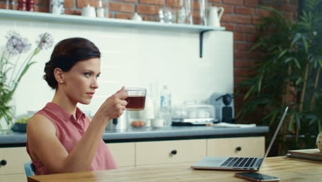 mujer de negocios escribiendo en la computadora en la cocina. mujer freelance terminando el trabajo.