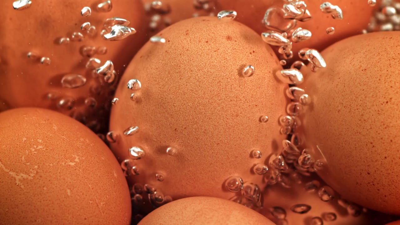 Close-up of Brown Eggs Boiling in Water with Bubbles