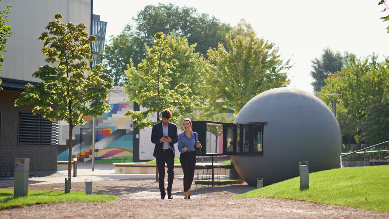 Friendly couple going corporate district in spring. Smiling workers hold coffee