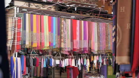 colorful textiles on hangers for sale in marrakesh medina, morocco