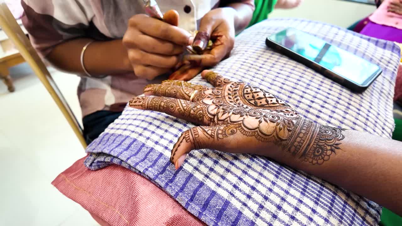 Primo piano di tatuaggio tradizionale all'henné Mehndi applicato sulla mano di una donna durante una cerimonia nuziale indiana