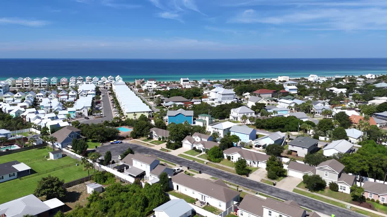 Panoramic drone movement over bright suburban community with distant sandy beach, Panama City Beach, Florida, USA