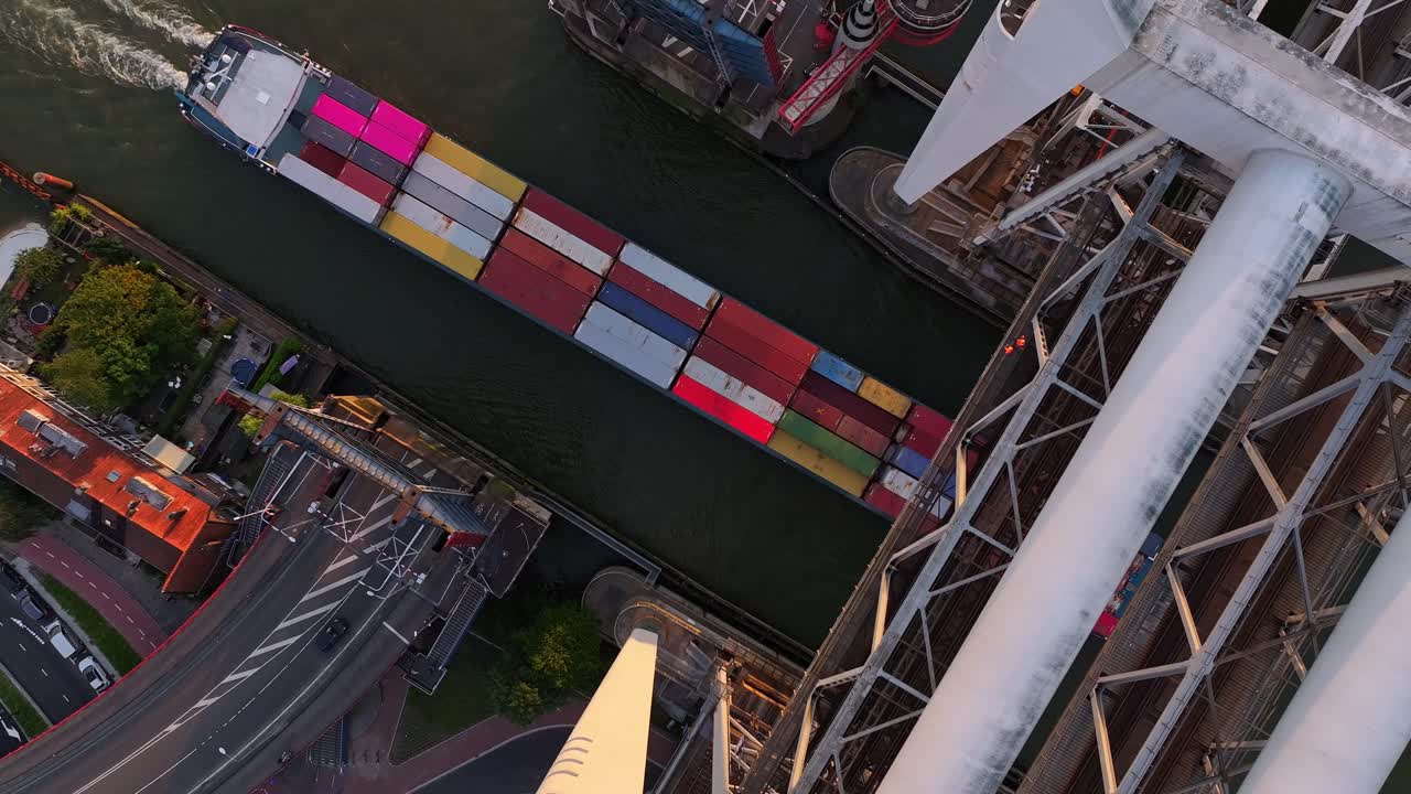 Large container ship passing an open road bridge and lifted rail bridge in Dordecht
