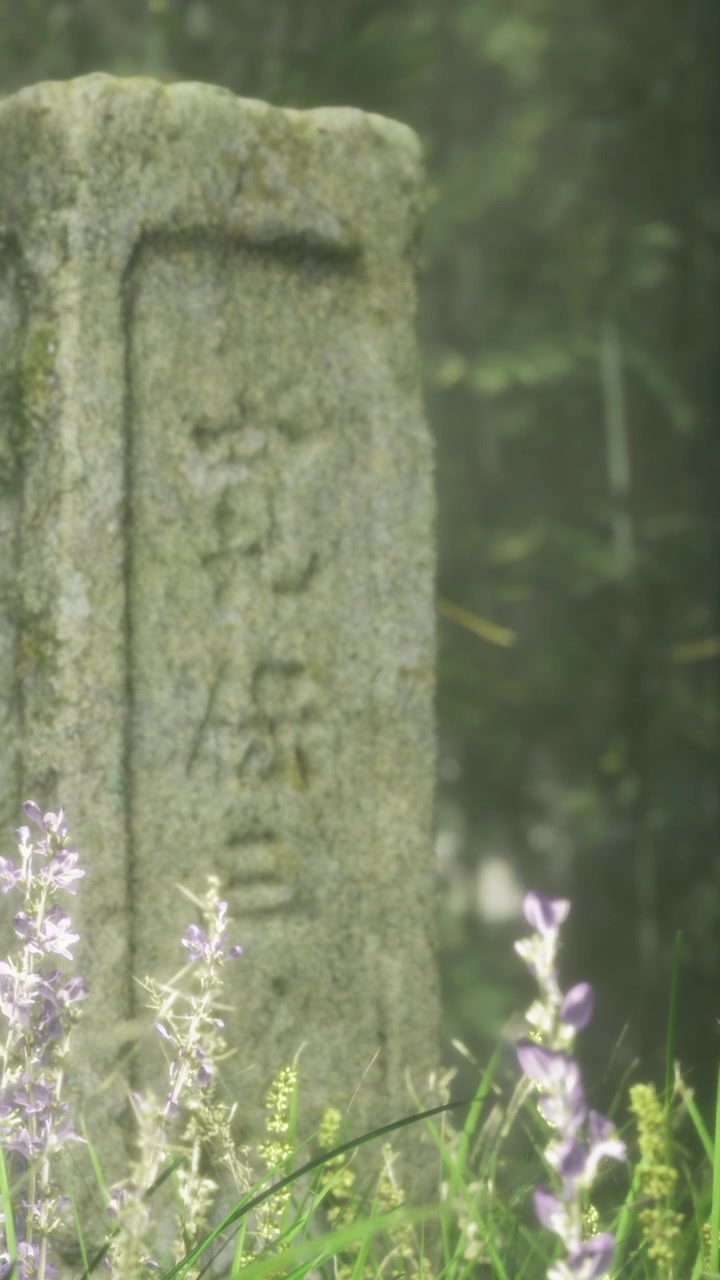 Stele di pietra con caratteri giapponesi e fiori selvatici in un ambiente verde.