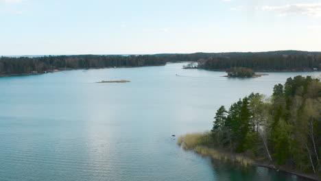 panning to the left a forested view transition into a the teal blue waters of a scandinavian lake.