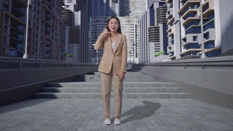 아시아 사업가 여성의 온몸은 따뜻하게 미소 짓고 도시 거리에서 전화 제스처에 대화하고 있습니다.