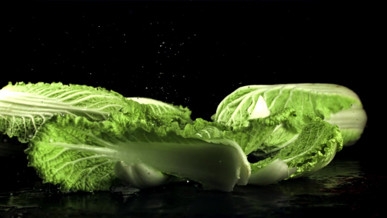 Fresh Green Cabbage Leaves Falling onto Wet Surface in Slow Motion