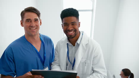 portrait of male doctor and nurse with clipboard discussing patient notes on stairs in hospital