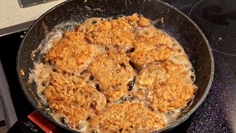 cooking crispy homemade patties in a skillet while oil sizzles and browns them to perfection on a hot stove top