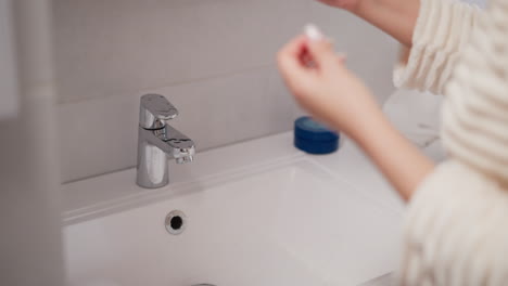 lavabo limpio con agua que fluye del grifo brillante en el baño. persona enjuaga la mano después de la crema pegajosa bajo el agua corriente en el inodoro en cámara lenta