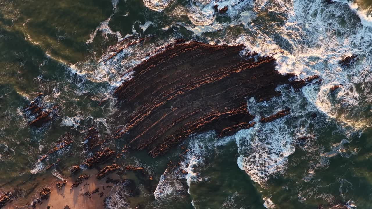 Waves breaking on a rock at sunset