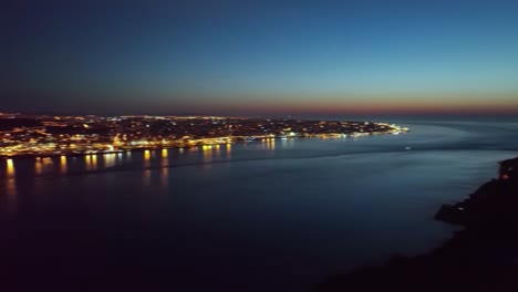 drone footage panning over river tejo, from pretty close to christo rei statue, towards ponte 25 abril and the city lights of lisbon