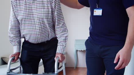 senior man using a walking frame with male nurse, mid section