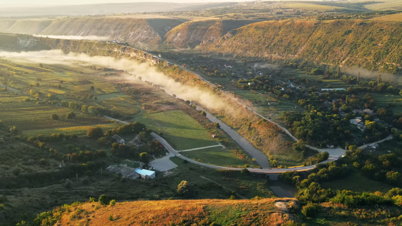 Aerial drone view of the Old Orhei at sunset. Valley with river and fog, village, hills in Moldova