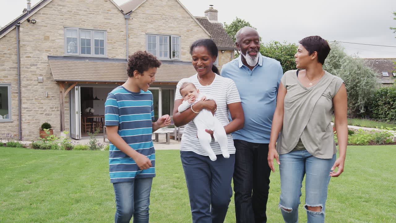 Multiculturele familie van meerdere generaties met baby wandelt thuis in de tuin