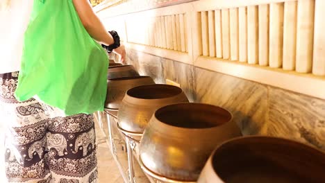 person donating coins into temple bowls