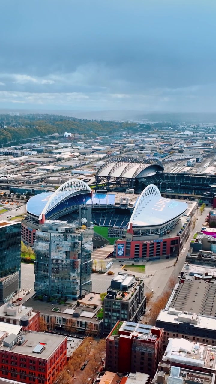 Krajobraz dzielnicy SoDo ze stadionem Lumen Field pośrodku. Seattle, Waszyngton, Stany Zjednoczone z lotu ptaka w pochmurny dzień. Wideo pionowe