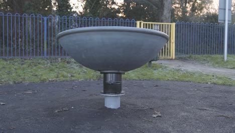 un carrusel de acero giratorio en un parque infantil vacío en un día nublado y frío en el centro de londres