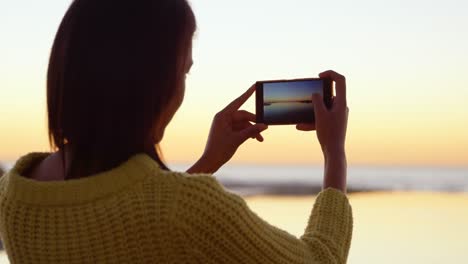 beautiful woman capturing sunset on mobile phone 4k