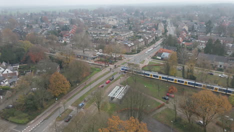 Blick-Aus-Der-Vogelperspektive-Auf-Den-Zug,-Der-über-Den-Bahnübergang-Fährt,-Während-Der-Verkehr-Wartet