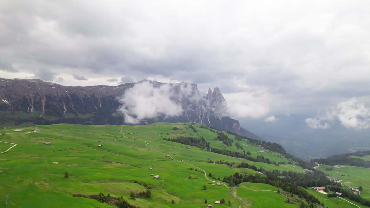 Đoạn phim trên không quay bằng flycam tại Dolomites, Ý, với đồng cỏ xanh ở phía trước và các đỉnh núi ở phía sau