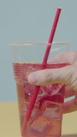 Vertical-Video-Summer-Holiday-Concept-With-Hand-Putting-Down-Cold-Drink-With-Ice-On-Yellow-Background-1