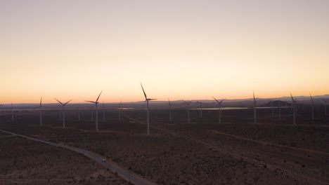 Car-Driving-down-desert-road-next-to-windmills,-mojave-desert,-mojave-california