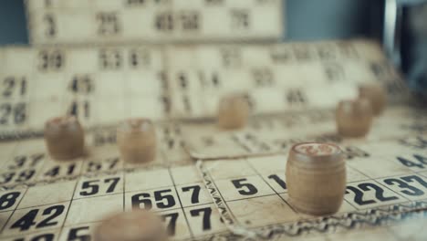 video macro de un tablero de bingo, luces de estudio, 120 fps, cámara lenta, dígitos de chips de madera, imágenes en bruto, juego de mesa de lotería vintage, números de cartas, empuje de grúa en movimiento suave