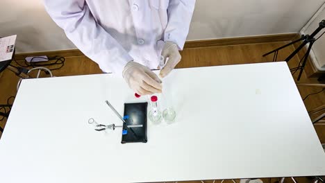 scientist conducts a chemical reaction using lead nitrate and potassium iodide on a lab table under bright lighting