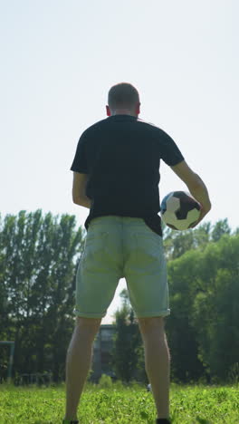 vista trasera de un hombre girando una pelota de fútbol a su alrededor mientras el abuelo y su nieto juegan al fútbol en un sendero cerca de un campo de hierba