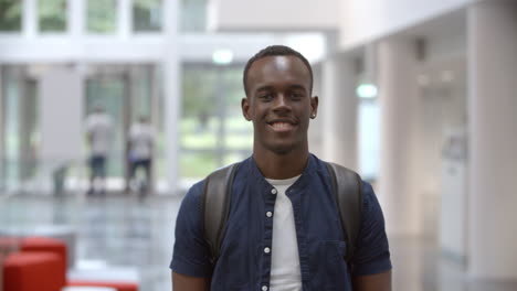 black male university student walking into focus in a lobby