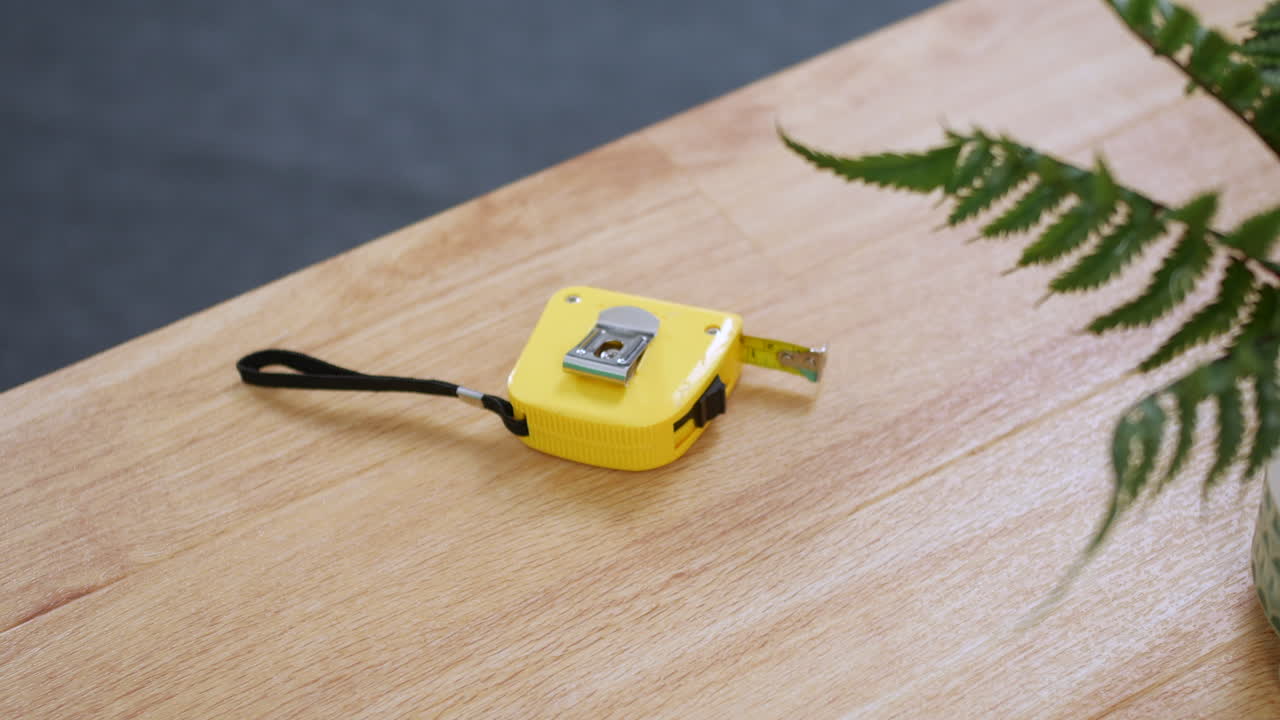 un hombre recogiendo una cinta métrica de un escritorio de mesa