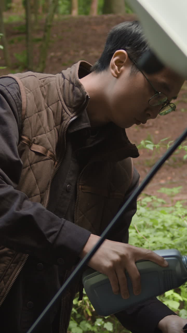 Man replenishing car fluids in the forest