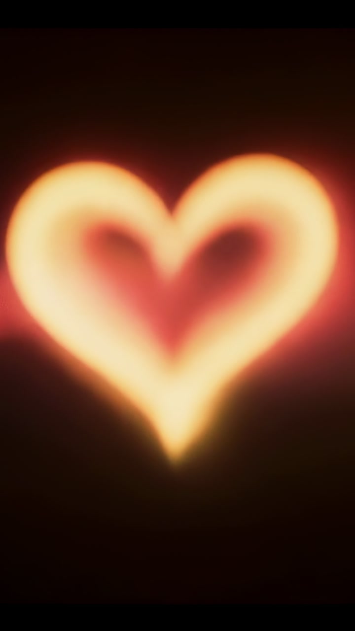 Vertical video: Forming heart glow with warm streak appearing on dark backdrop, creating twin halos