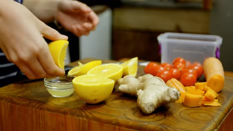 Woman-squeezing-lemon-in-bowl-at-cafe-kitchen-4k