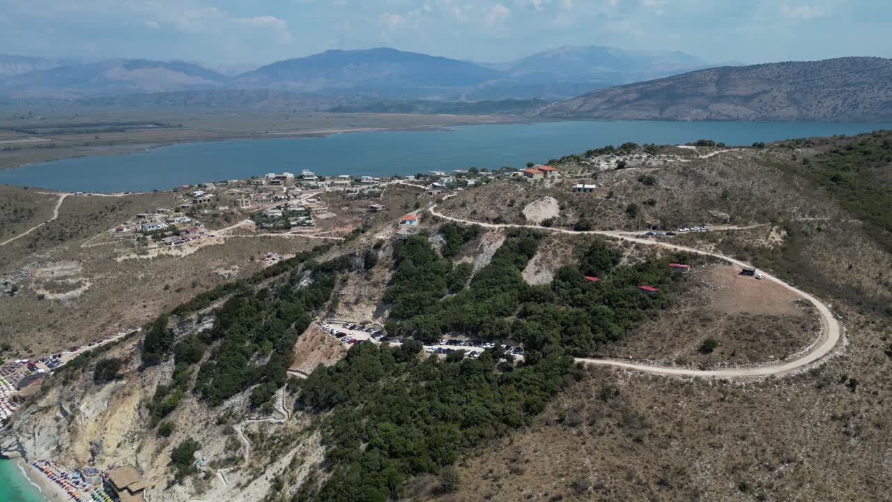 A drone captured a panoramic view of a scenic landscape featuring a lake, mountains, and a few scattered homes.