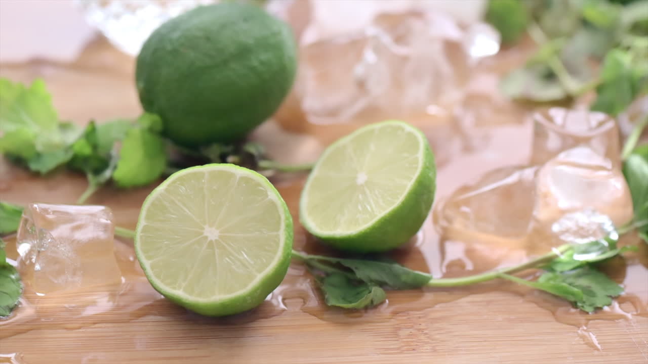 Close up of cut up lime with ice and mint on a wooden cutting board