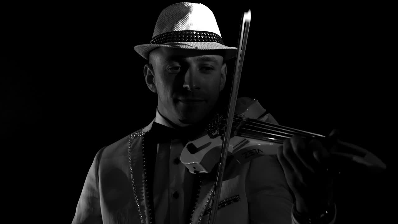 음악가 가 검은색 배경 에 바이올린 을 연주 하고 있다