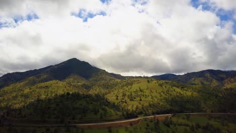 Aerial-pan,-highway-winding-along-lush-green-mountains-in-California,-cloudy-day